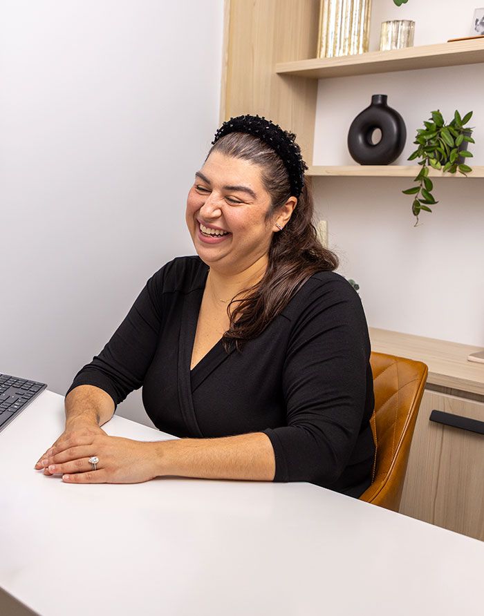 Canary Dental staff member smiling warmly while seated at a modern office desk