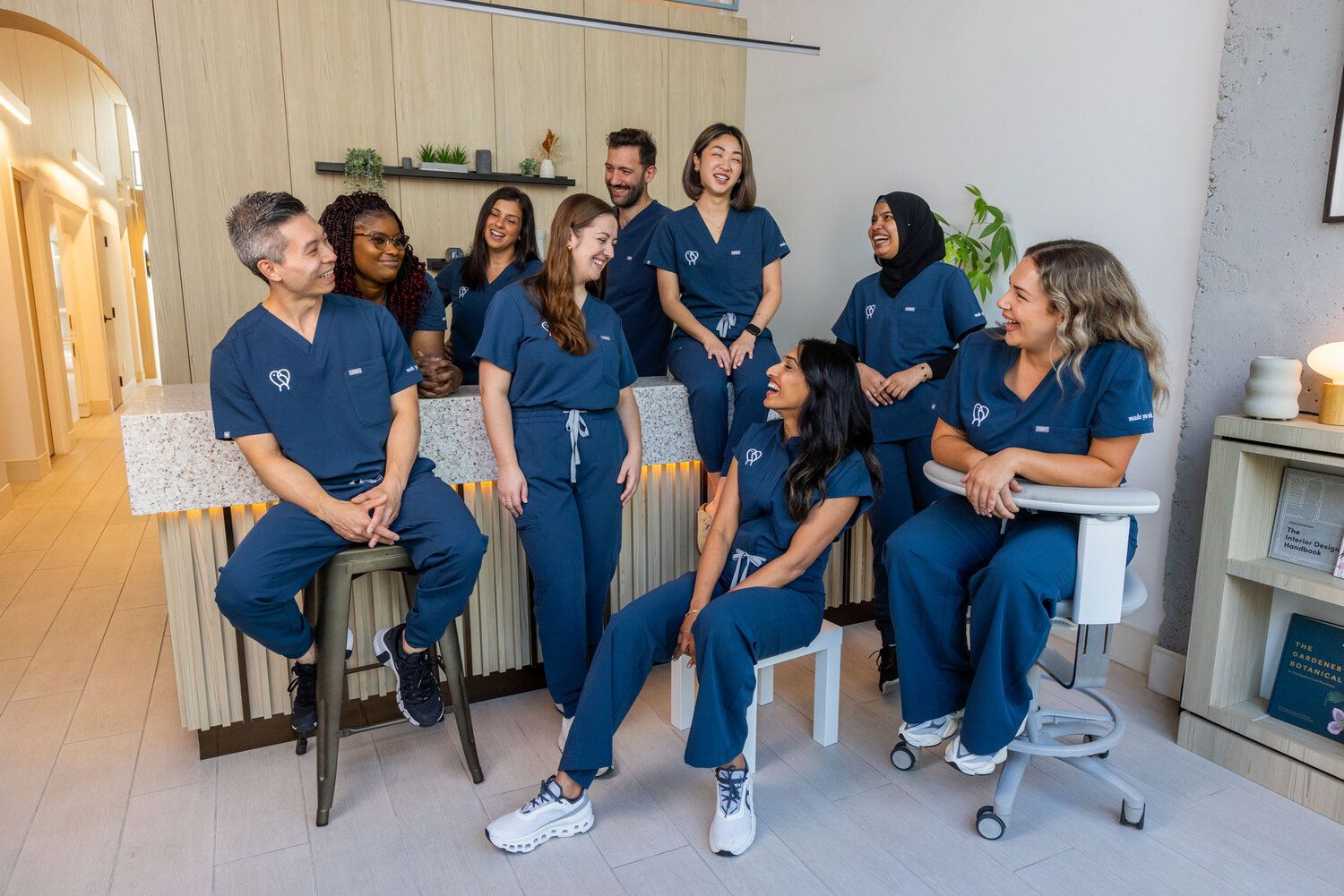 Canary Dental team in blue scrubs smiling and chatting together at the modern clinic reception area